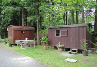 Deux petites cabanes en bois et un banc à Camping Isny, hébergement glamping de luxe en Baden-Württemberg.