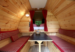 Intérieur d’un hébergement glamping avec murs en bois, banquettes et lit, Camping Isny - Luxe glamping Baden-Württemberg.