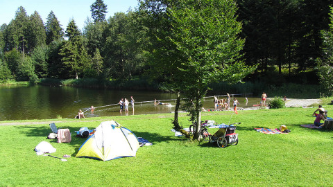 Kampeerders bij een meer met tent, ontspanning en zwemmen op Camping Isny - Luxe glamping Baden-Württemberg.