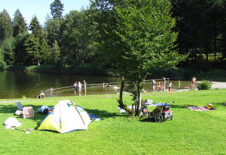 Kampeerders bij een meer met tent, ontspanning en zwemmen op Camping Isny - Luxe glamping Baden-Württemberg.