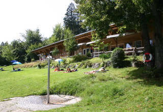 Grasveld bij Camping Isny met zonaanbidders en houten lodge, luxe glamping in Baden-Württemberg.