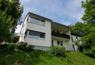 Alloggio glamping bianco al Camping Isny di Baden-Württemberg, immerso nel verde rigoglioso.