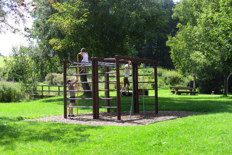 Niños juegan en estructuras de escalada en Camping Isny - Luxe glamping Baden-Württemberg, zona verde amplia.