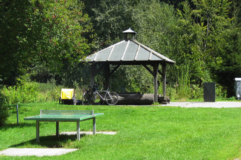Outdoor view at Camping Isny, Baden-Württemberg featuring a ping pong table, bicycle and covered glamping spot.