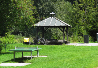 Outdoor view at Camping Isny, Baden-Württemberg featuring a ping pong table, bicycle and covered glamping spot.