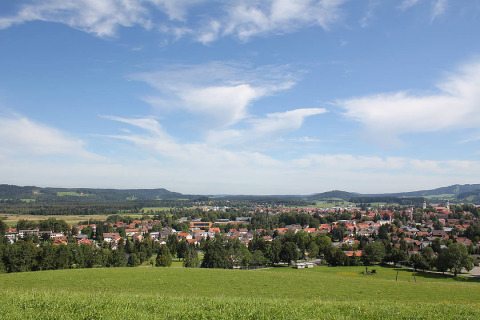 Uitzicht op Camping Isny - Luxe glamping Baden-Württemberg met groene velden en dorpshuizen, onder blauwe lucht.