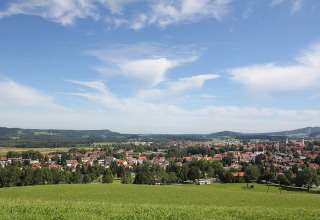Blick auf Camping Isny - Luxe glamping Baden-Württemberg mit grünen Wiesen und Dorfhäusern im Hintergrund.