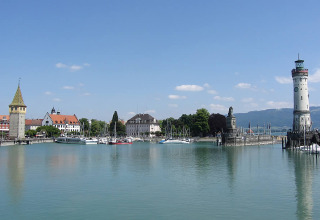Vista sul porto di Lindau con faro e barche, ideale per il glamping a Camping Isny in Baden-Württemberg.
