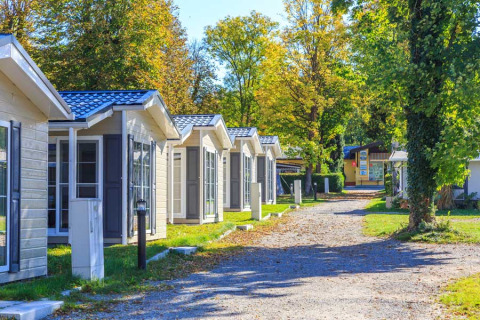 Camping Pilsensee - Stacaravans Beieren: File di case mobili accoglienti tra alberi verdi in campeggio soleggiato.