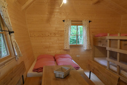 Interno accogliente di una casetta in legno al Boomhutpark Voglsam, Baviera, con letto doppio e a castello.