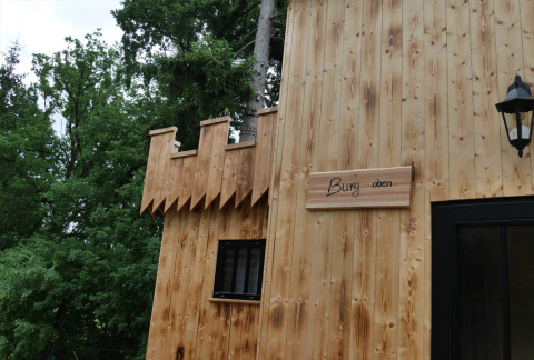 Cabane en bois façon château au Boomhutpark Voglsam glamping, entourée d’arbres en Bavière.