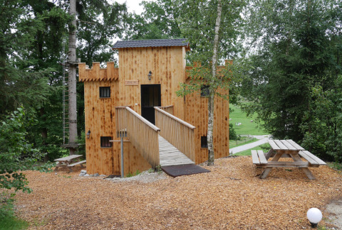 Træhytte glamping indkvartering formet som et slot i Boomhutpark Voglsam, omgivet af skov og picnicborde.