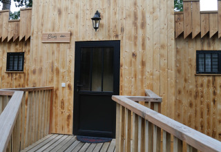 Glamping accommodation with wooden facade and black door at Boomhutpark Voglsam in Bavaria.