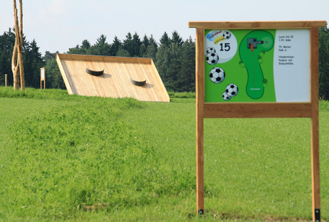 Voetgolfbaan en infobord op het grasveld van Boomhutpark Voglsam glamping in Beieren, Duitsland.