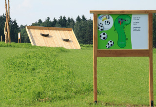 Fußballgolfbahn und Informationstafel auf einer grünen Wiese im Boomhutpark Voglsam in Bayern.