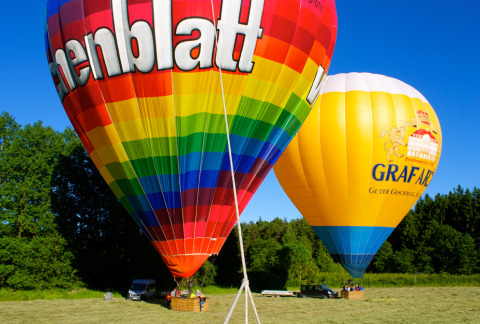 Twee kleurrijke luchtballonnen startklaar op een veld bij Boomhutpark Voglsam, Beieren.