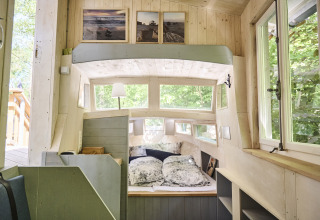 Interieur van Baumschiffhotel Boomschepen Beieren, knusse glamping met groot bed en vele ramen.