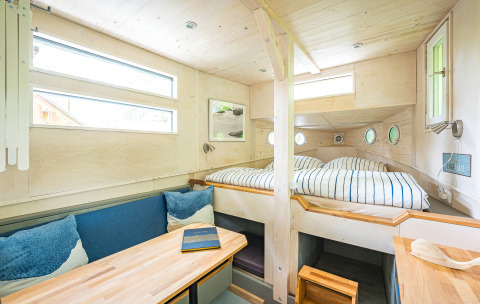 Lyse, hyggelige glamping-værelser med moderne træinteriør og dobbeltseng på Baumschiffhotel i Bayern.