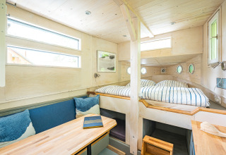 Alloggio glamping luminoso con interni in legno, letto matrimoniale e zona relax al Baumschiffhotel Baviera.