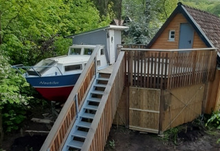 Alojamiento glamping único en Baumschiffhotel con barco y cabaña sobre plataforma de madera en el bosque.