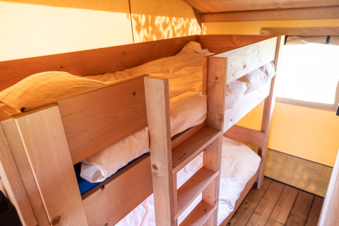 Interieur van een gezellige safaritent met houten stapelbedden bij Camping Natuurlijk de Veenhoop in Friesland.