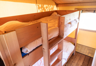 Binnenzicht van een knusse safaritent met houten stapelbedden bij Camping Natuurlijk de Veenhoop, Friesland.