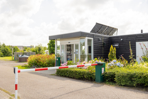 Receptionen ved Camping Natuurlijk de Veenhoop - Safaritenten Friesland med en bom og smukke blomster foran.