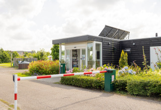 Reception e sbarra d'ingresso al Camping Natuurlijk de Veenhoop - Safaritenten Friesland, con fiori colorati davanti.