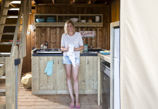 Donna sorridente in una cucina in legno di una tenda safari al Weekend Glamping Resort sul Lago di Garda.