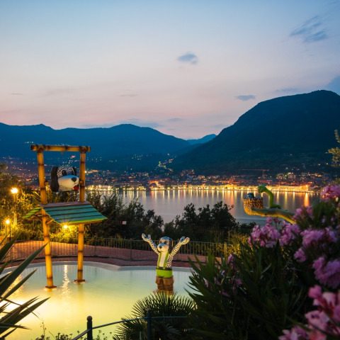 Blick auf das Weekend Glamping Resort am Gardasee bei Sonnenuntergang, mit lustigen Figuren und Bergkulisse.