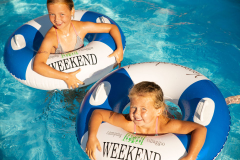 Twee blije kinderen spelen in het zwembad met zwembanden bij Weekend Glamping Resort aan het Gardameer.