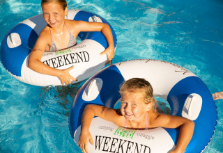 Zwei fröhliche Kinder spielen mit Schwimmringen im Pool des Weekend Glamping Resort am Gardasee.