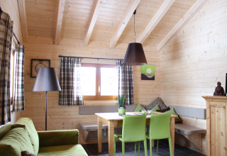 Acogedora cabaña glamping con paredes de madera, sillas verdes y ventanas grandes en la Selva Negra.