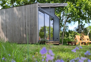 Sistemazione glamping moderna a Uitstek - Tiny Houses Drenthe, circondata da alberi e fiori selvatici.