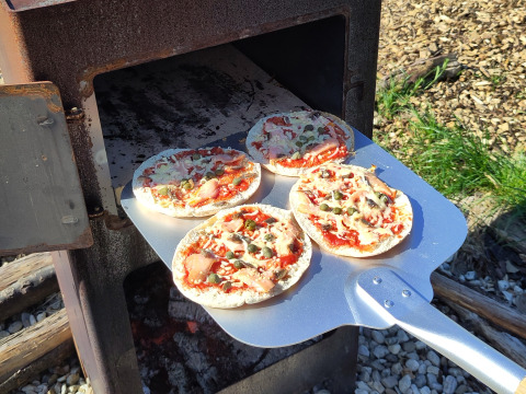 Cuisson de mini pizzas dans un four extérieur à Uitstek - Tiny Houses Drenthe, hébergement en glamping.