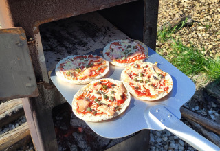 Mini pizza's worden gebakken in een buitenoven bij Uitstek - Tiny Houses Drenthe tijdens het glampen.