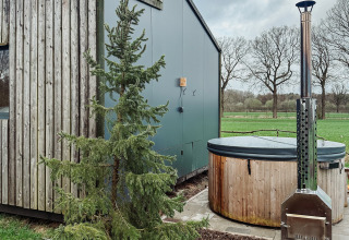 Moderne Glamping-Unterkunft mit Holzfassade, Hot Tub und grüner Landschaft bei Uitstek - Tiny Houses Drenthe.