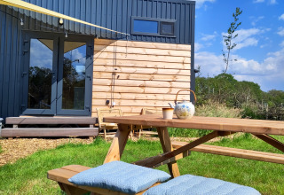 Tavolo da picnic con cuscini e teiera davanti a una tiny house moderna di Uitstek - Tiny Houses Drenthe.