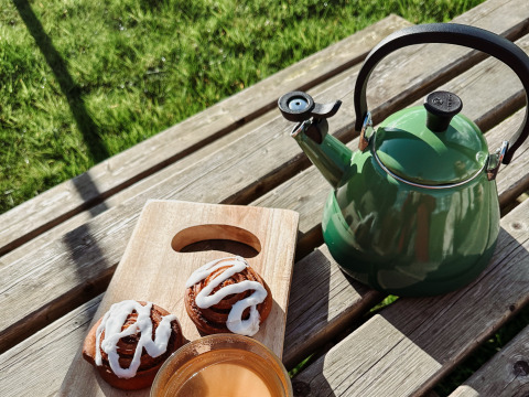 Groene waterkoker, koffie en kaneelbroodjes op houten tafel bij Uitstek - Tiny Houses Drenthe glamping.