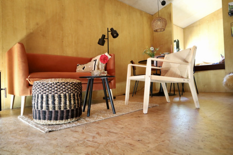 Interior moderno y acogedor de 'Uitstek - Tiny Houses Drenthe', con asientos elegantes y decoración cálida.