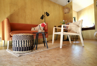 Interior moderno y acogedor de 'Uitstek - Tiny Houses Drenthe', con asientos elegantes y decoración cálida.