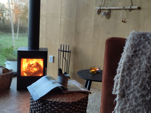 Gemütliches Glamping mit Kaminofen, Korbmöbeln und Kerzen im Uitstek Tiny House Drenthe, Niederlande.