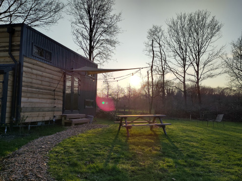 Udendørsbillede af glamping indkvartering ved Uitstek - Tiny Houses Drenthe med bordbænk og solnedgang.