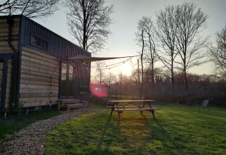 Udendørsbillede af glamping indkvartering ved Uitstek - Tiny Houses Drenthe med bordbænk og solnedgang.