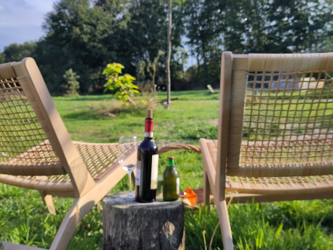 Due sedie a sdraio e un tavolo con bottiglia di vino nel verde a Uitstek - Tiny Houses Drenthe.