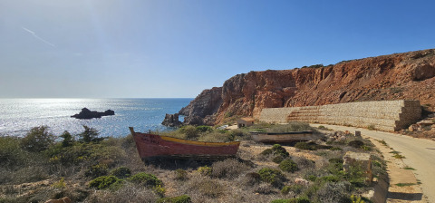 Paisaje costero con barcos viejos y acantilados cerca de Casa da Vinha - Glamping Lodges en Alentejo, Portugal.