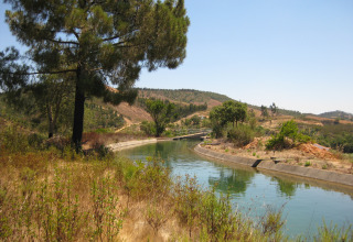 Kanaallandschap nabij Casa da Vinha - Glamping Lodges in Alentejo, Portugal, omgeven door heuvels en bomen.