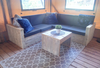 Area lounge accogliente a Casa da Vinha - Glamping Lodges in Alentejo con mobili in legno e cuscini morbidi.