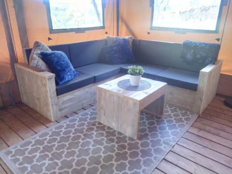 Gezellige loungehoek in Casa da Vinha - Glamping Lodges in Alentejo met houten meubels en zachte kussens.