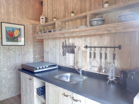 Zona de cocina en Casa da Vinha - Glamping Lodges en Alentejo, con paredes de madera y estantes abiertos.